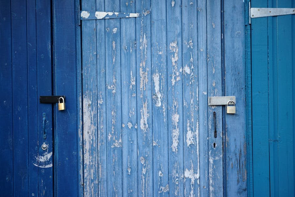 Weathered blue wooden doors with padlocks, showcasing rustic charm and security.