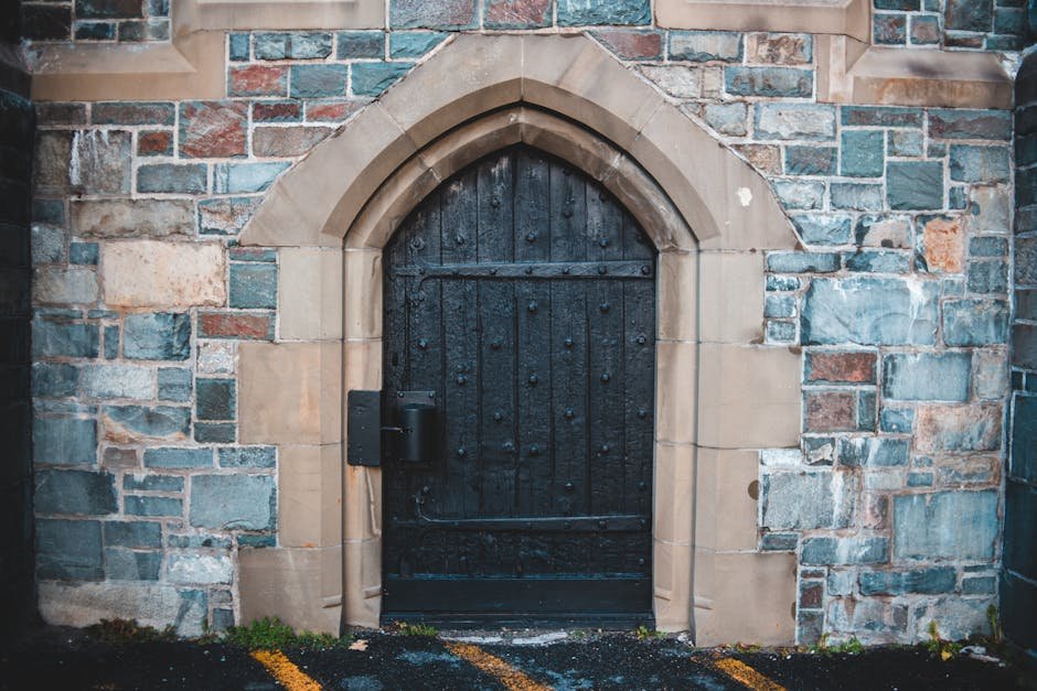 Close-up of a gothic archway featuring a black wooden door set in a stone facade.