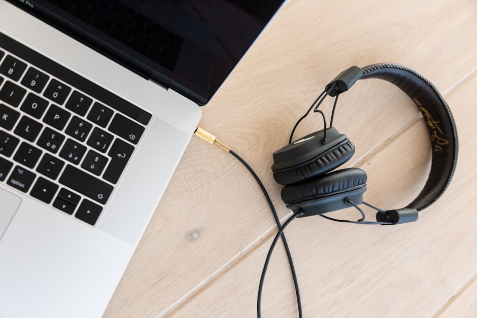 Close-up of a laptop and headphones on a wooden desk, showcasing modern technology.