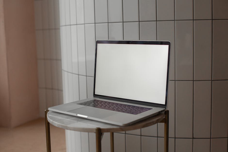 A sleek laptop with a blank screen on a round marble-top table indoors.