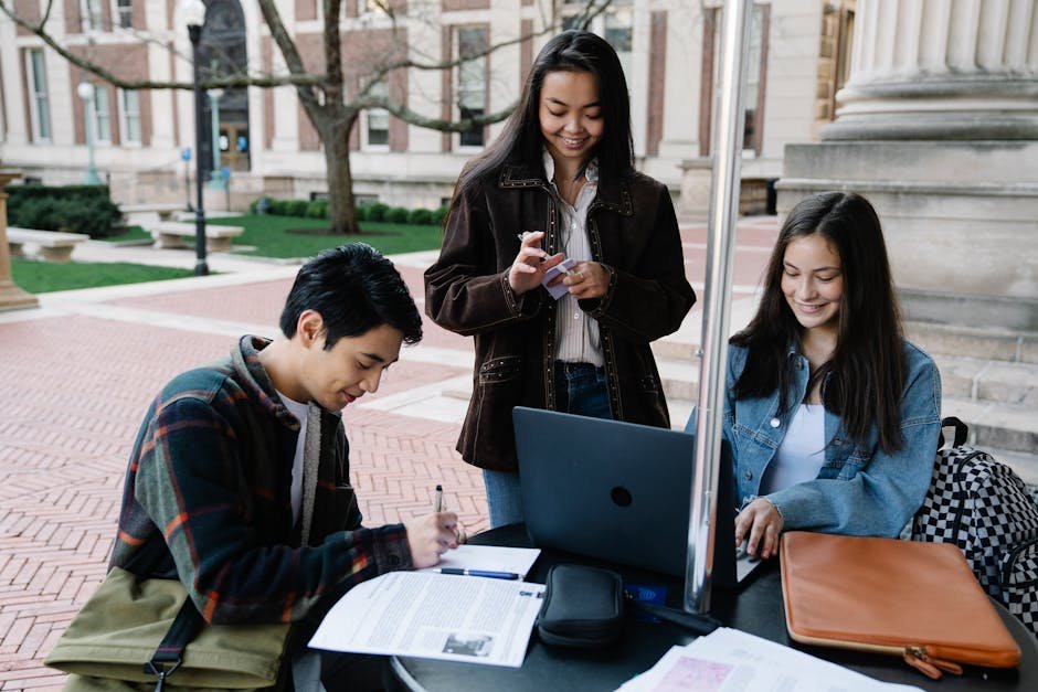 A group of students working on a project outdoors, showcasing teamwork in a university setting.